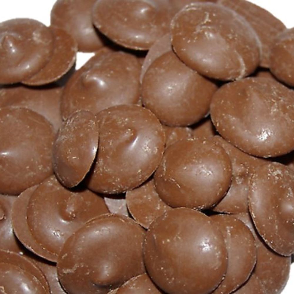 A close-up of chocolate carob drops, similar to candy, intended as a treat for dogs.