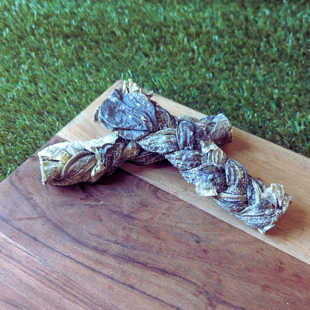 Braided pieces of mackerel skin on a wooden surface, which is used as a natural dog treat.