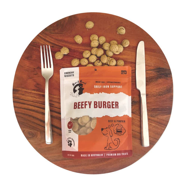 Mimi & Munch Beefy Burger natural dog treats in a resealable pouch, playful image shpowing treats spilling from pouch alongside knife and fork
