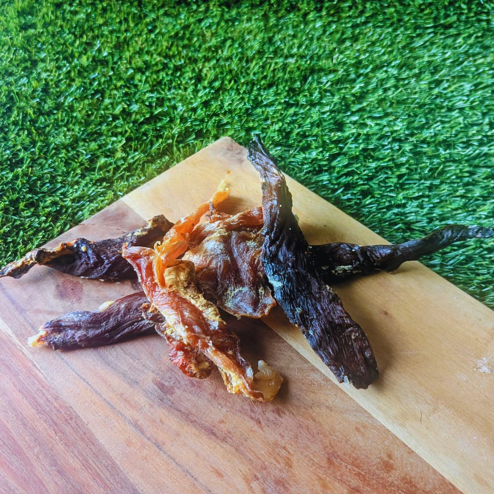 crocodile jerky on a wooden board with grass in the background