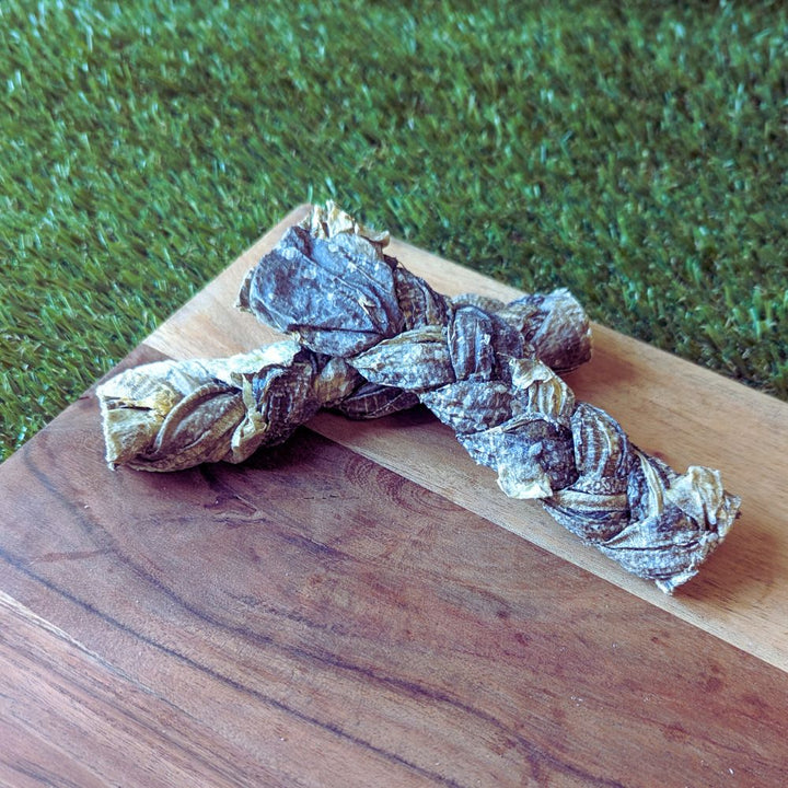 Braided pieces of mackerel skin on a wooden surface, which is used as a natural dog treat.