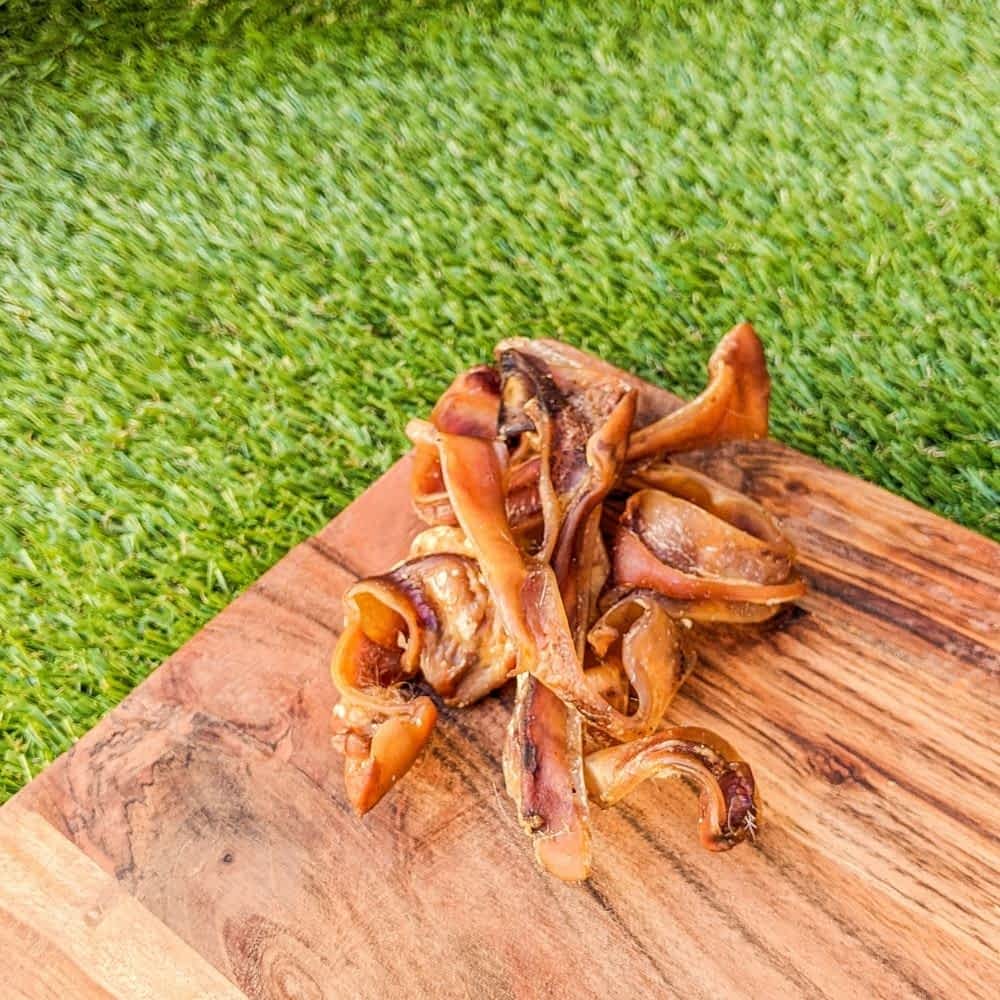 Pile of Australian Pig Ear Strips, a natural pork chew designed for puppies, small dogs, and seniors for gentle dental health | Bonza Dog Treats
